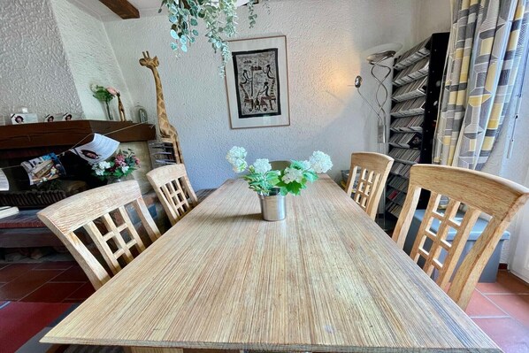 A dining area with a wooden table and chairs, a vase with flowers, and a giraffe decoration on the wall. - Charming holiday home with garden (Wissembourg)
