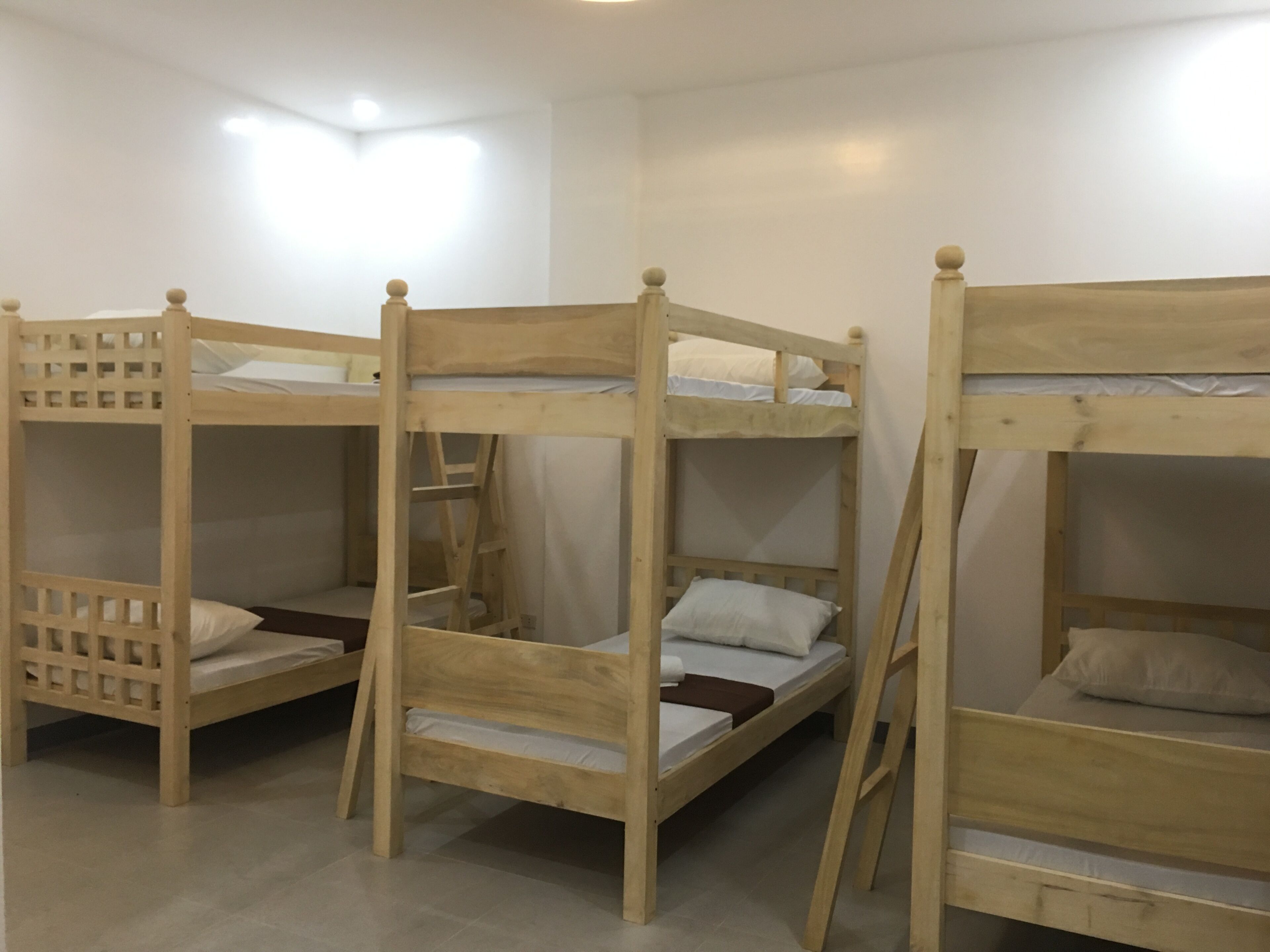 A room with three bunk beds, each with a ladder and a wooden headboard.