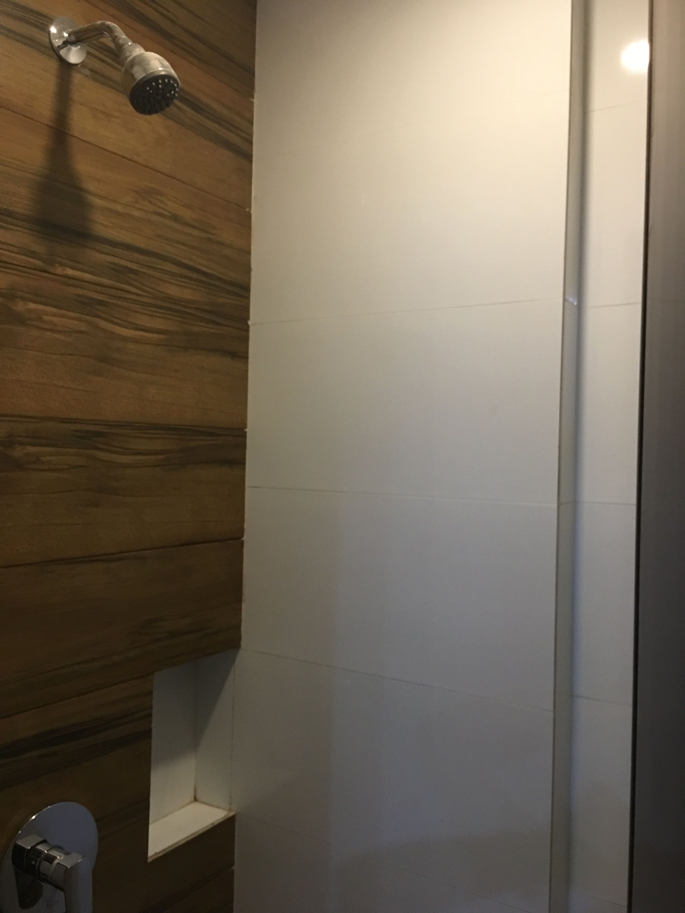 Une douche avec un mur en bois et des carreaux blancs.