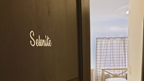 Una habitación de hotel con una cama, una mesita y una cortina.