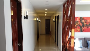 Un pasillo moderno de hotel con piso pulido, puertas de madera e iluminación empotrada.