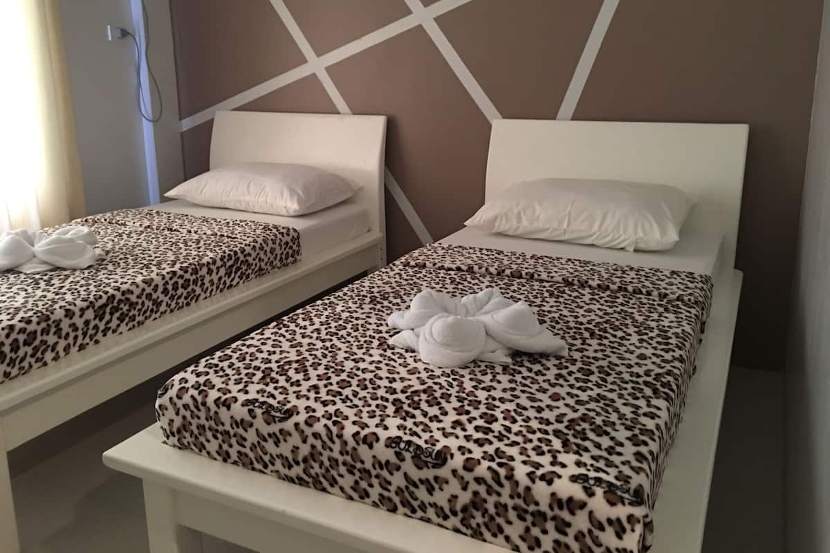 Two single beds with leopard print bedding, white headboards, and white pillows.