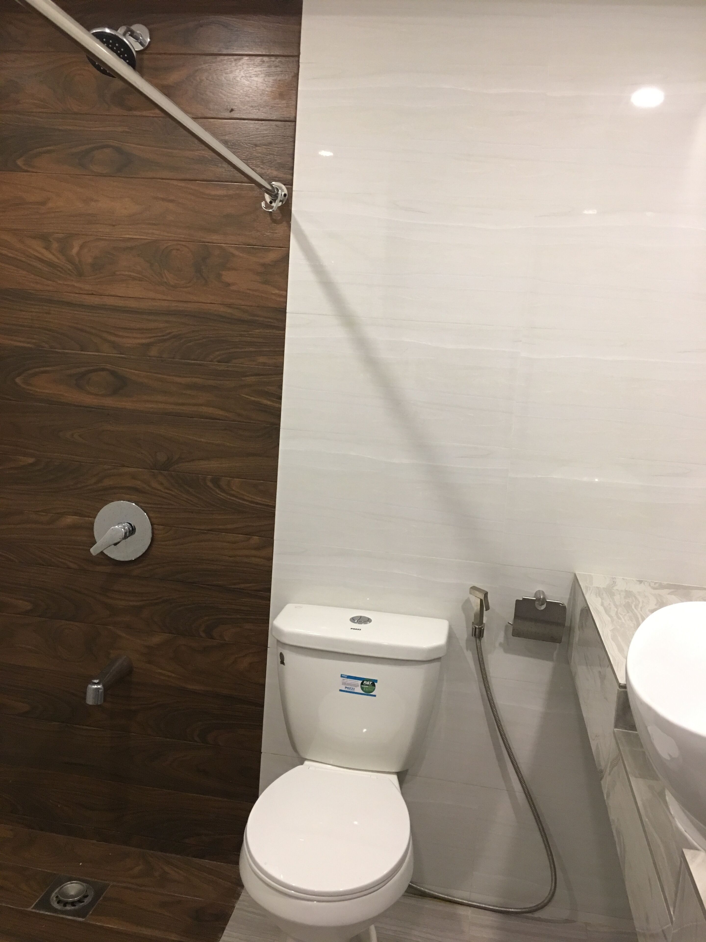 Une salle de bain avec des toilettes blanches, un espace douche et un plancher en bois.