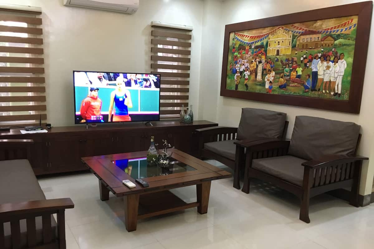 A living room with a TV, wooden furniture, and a painting on the wall.