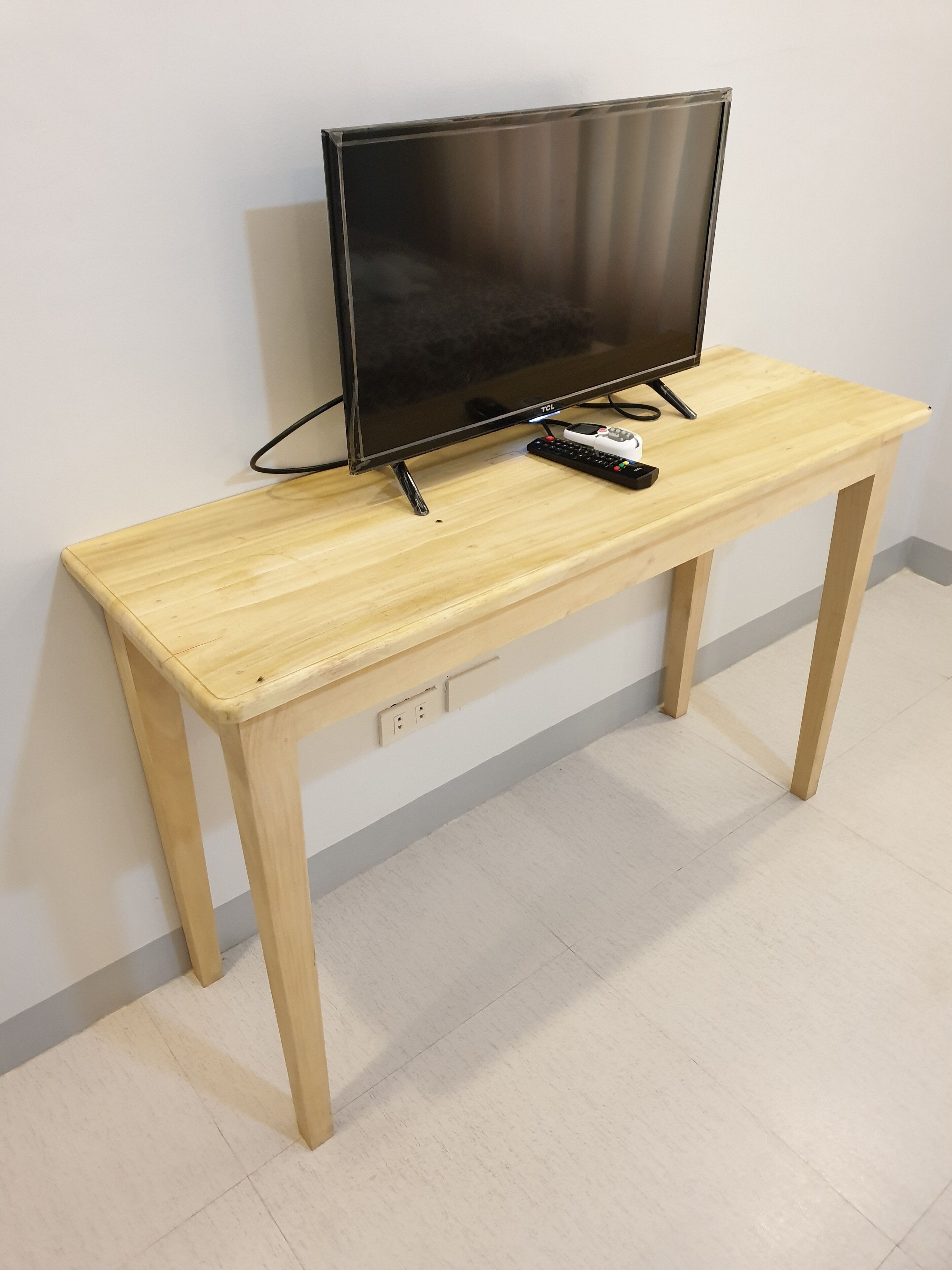 A wooden TV stand with a flat-screen TV and a remote control.