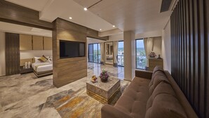 A modern hotel room with a large bed, a flat-screen TV, a sofa, and a balcony with a city view. - Regenta Central Imperial Candolim Goa (Candolim)