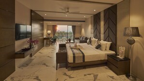 A modern hotel room with a large bed, a desk, a chair, and a balcony with a view. - Regenta Central Imperial Candolim Goa (Candolim)
