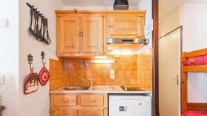 A compact kitchen with wooden cabinets, a sink, and a small refrigerator. - 4/6 PERSON RENTAL - LE FAYARD- 800M FROM THE CENTER (Arâches-la-Frasse)