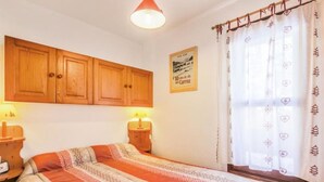 A bedroom with a bed, wooden cabinets, a nightstand with a lamp, and a window with curtains. - 4/6 PERSON RENTAL - LE FAYARD- 800M FROM THE CENTER (Arâches-la-Frasse)