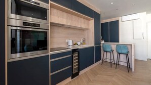 Une cuisine moderne dotée d’appareils électroménagers intégrés, d’un coin bar avec deux tabourets et d’un plancher en bois.