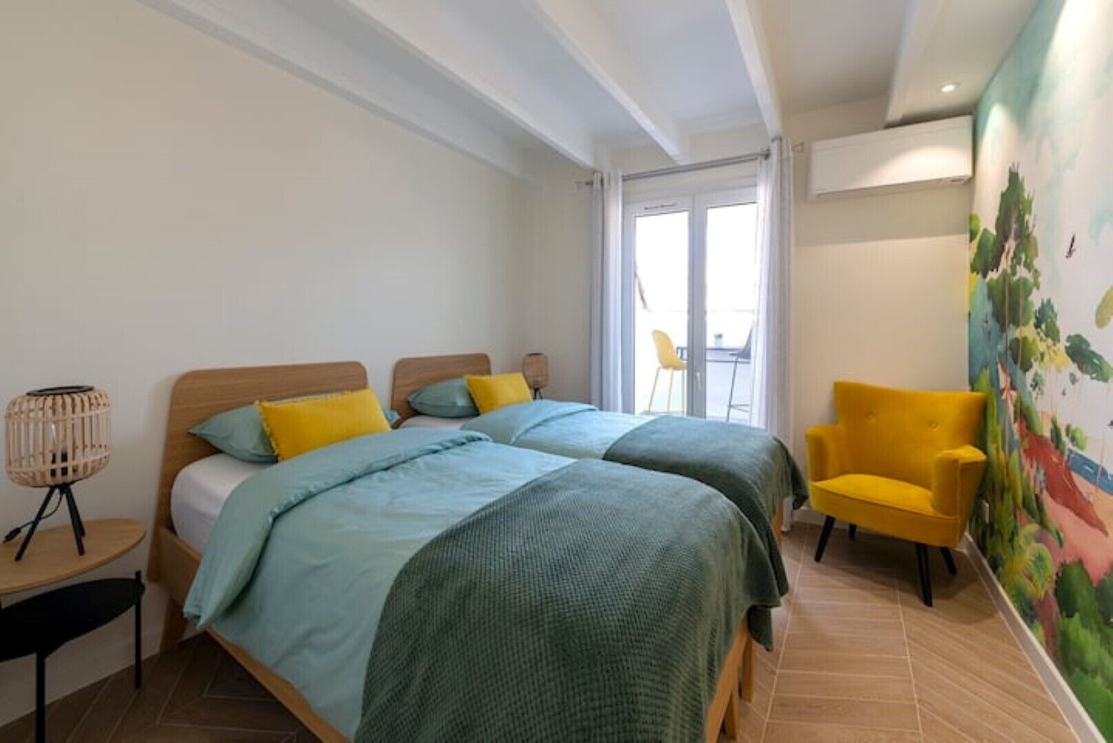 A bedroom with two beds, a chair, a lamp, and a mural on the wall.