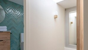Un couloir avec un plancher en bois, une porte blanche et une petite fenêtre.