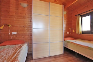 A wooden cabin room with a sliding door, two beds, and a window with curtains. - Bungalow Moijama 7, Puerto Naos (Puerto Naos)