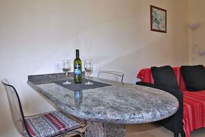 A dining table with a bottle and glasses, a chair with a patterned cushion, and a red sofa with black cushions. - Bungalow Moijama 2, en Puerto Naos (Puerto Naos)