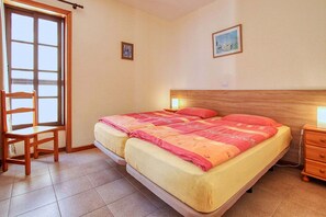 Ein Schlafzimmer mit Doppelbett, Holzstuhl, Nachttisch und Fenster mit Aussicht.
