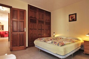 Un dormitorio con cama, un armario de madera, una mesita de noche y una lámpara.
