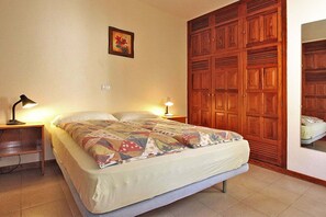 A bedroom with a bed, two bedside lamps, a wooden wardrobe, and a framed picture on the wall. - Bungalow Moijama 4, en Puerto Naos (Puerto Naos)