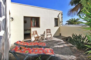 Eine Terrasse mit zwei Liegestühlen, einem Tisch, einem kleinen Tisch und zwei Stühlen.