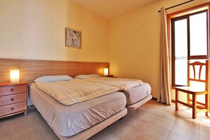 A bedroom with a double bed, bedside tables, a nightstand, a chair, and a window with curtains. - Bungalow Moijama 10, en Puerto Naos (Puerto Naos)