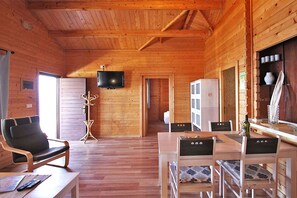 A wooden cabin interior with a dining table, chairs, a television, and a coat rack. - Bungalow Moijama 12, Puerto Naos (Puerto Naos)