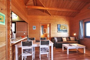 Ein Holzinterieur mit Essbereich, einer Couch und einem Gemälde an der Wand.