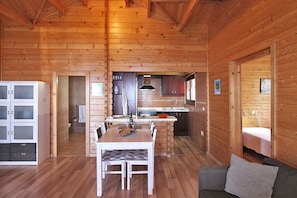 A wooden cabin interior with a dining area, kitchen, and a sleeping area. - Bungalow Moijama 12, Puerto Naos (Puerto Naos)