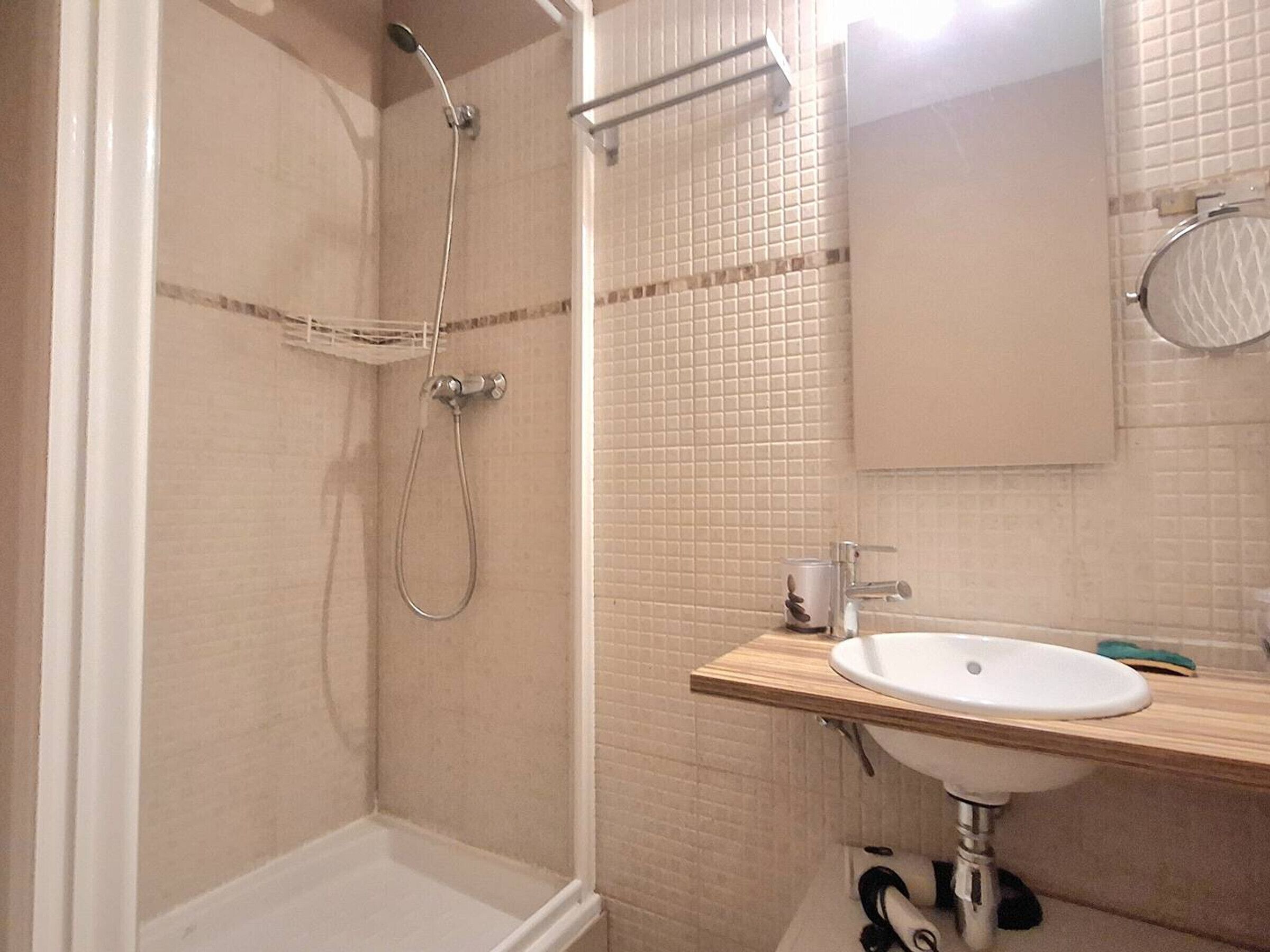 A bathroom with a shower, a sink, and a mirror.
