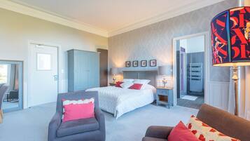 A bedroom with a bed, two armchairs, a nightstand, and a lamp.