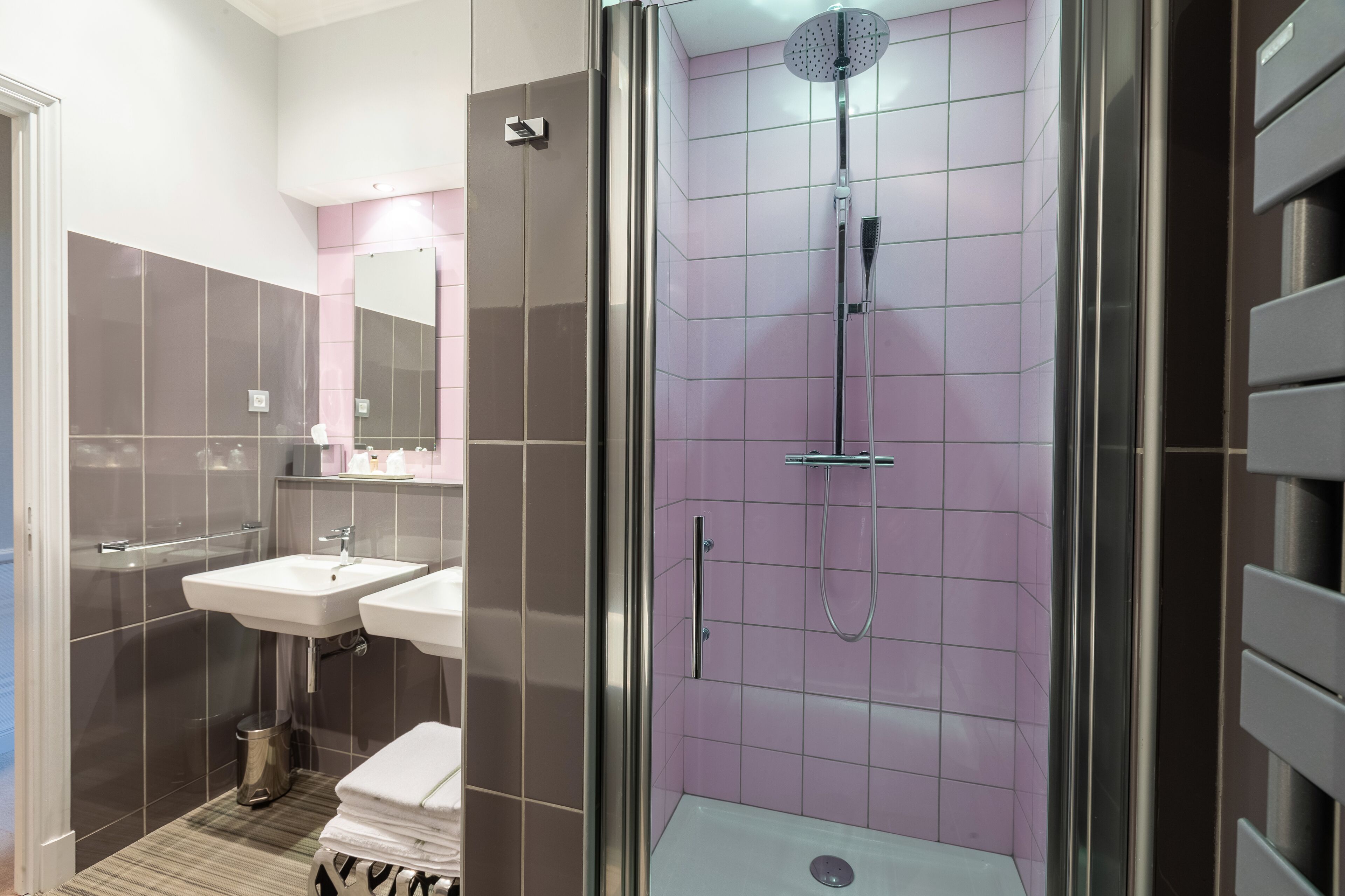Un baño moderno con ducha de vidrio, dos lavamanos y un mueble de tocador con espejo.