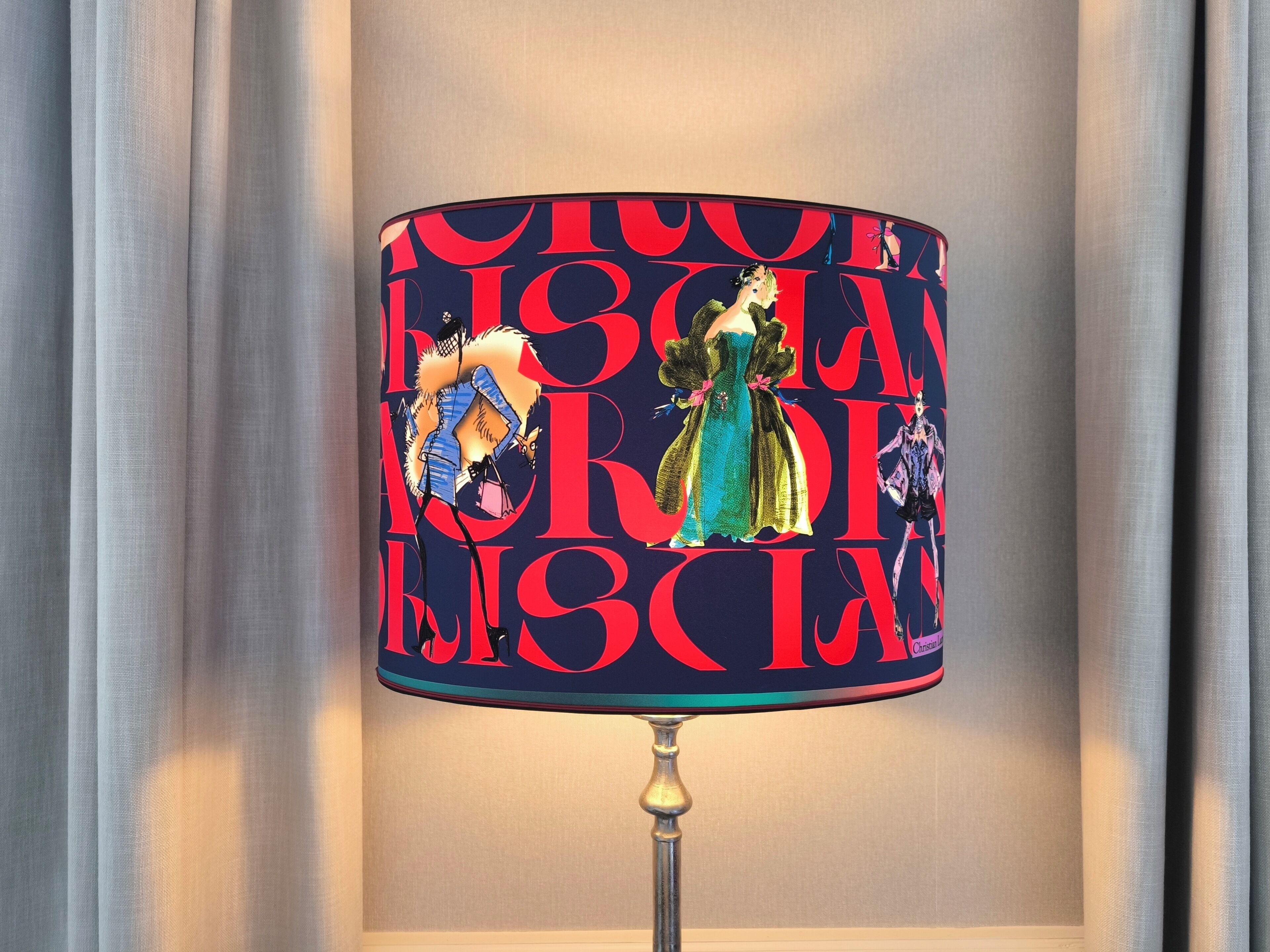 Een lamp met een decoratieve kap met abstracte figuren en opvallende tekst.