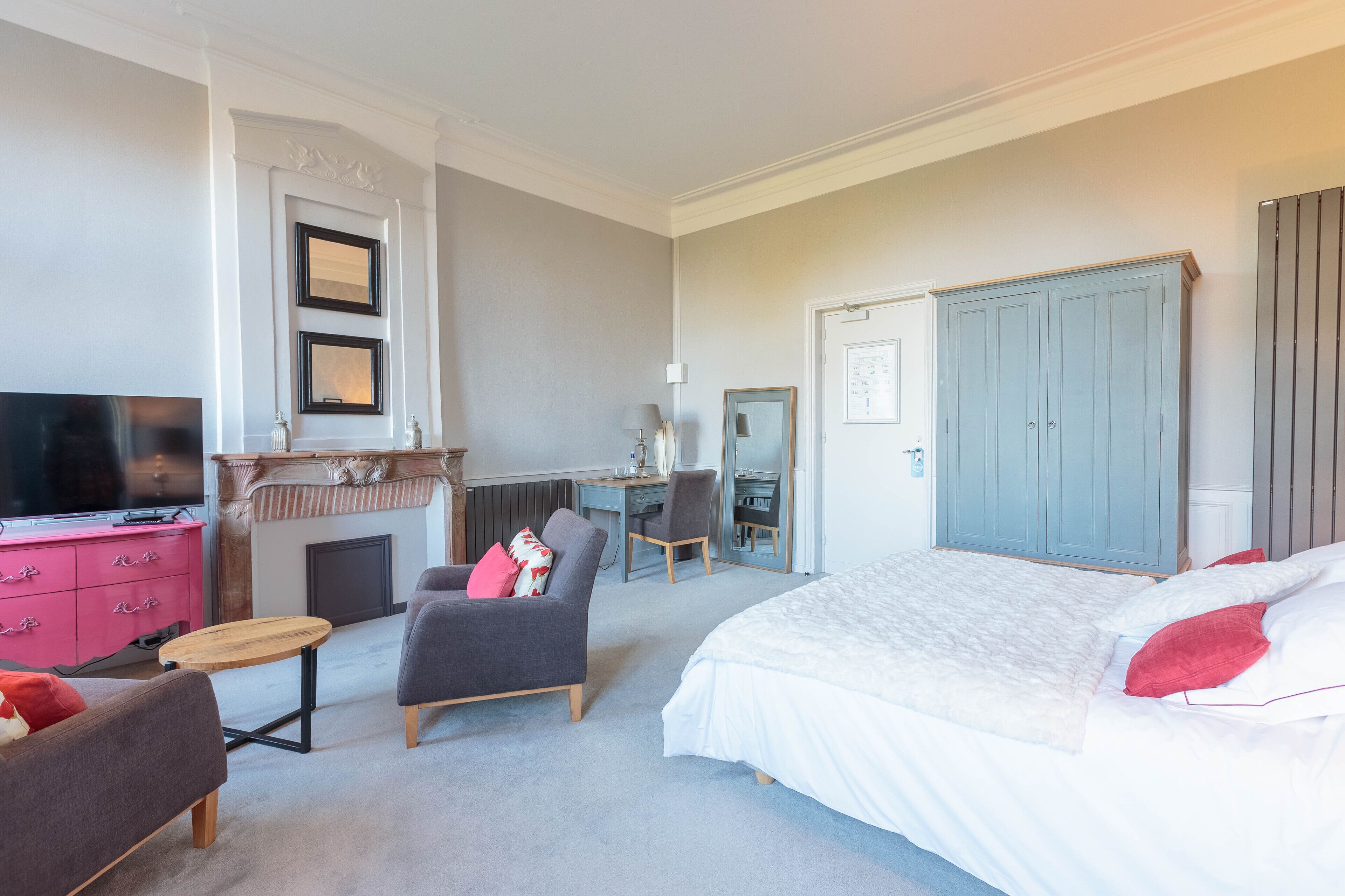 Une chambre à coucher avec un grand lit, un bureau, une chaise, une télévision et une armoire.