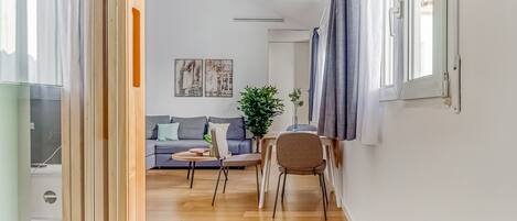 Un salon moderne avec un canapé, deux fauteuils, une petite table et une plante en pot.