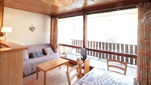 A cozy room with a wooden ceiling, a sofa, a table, and a TV.