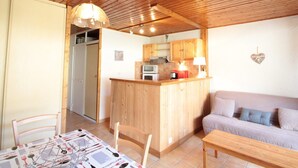 A cozy kitchen with wooden cabinets, a central island, and a dining area with a table set for four.
