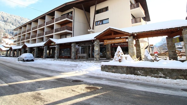 A multi-story hotel with balconies, a covered entrance, and a snow-covered ground.