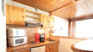 A compact kitchen with wooden cabinets, a microwave, a coffee maker, and a dishwasher.