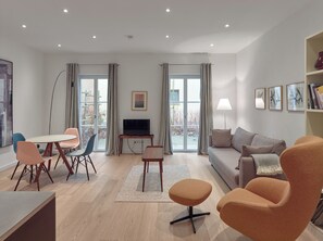 Una sala moderna con un sofá, sillas, un televisor y una estantería.