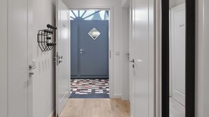 A hallway with white doors, a patterned rug, and a blue accent wall. - Gästehaus Cantzheim I Ferienwohung Fuchs - Cantzheim.dorf (Kanzem)