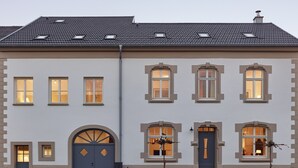 A two-story building with a symmetrical facade, featuring a central entrance with a blue door, flanked by two windows on each side. - Gästehaus Cantzheim I Ferienwohung Fuchs - Cantzheim.dorf (Kanzem)