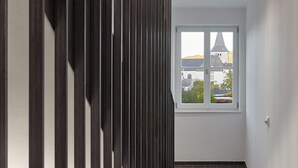 A hallway with a patterned floor, a window with a view of buildings, and a ceiling light. - Gästehaus Cantzheim I Ferienwohnung Ritterpfad - Cantzheim.dorf (Kanzem)
