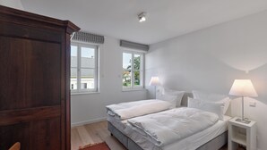 A bedroom with a double bed, two bedside tables with lamps, a wooden wardrobe, and a window with a view of the outside. - Gästehaus Cantzheim I Ferienwohnung Ritterpfad - Cantzheim.dorf (Kanzem)