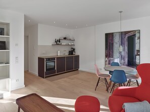 A modern kitchen with a dining area, including a red sofa and blue chairs.