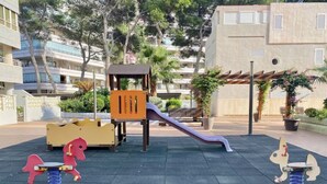 Une aire de jeux avec un toboggan et deux jeux montés sur ressort.