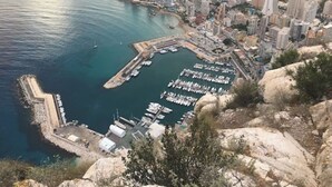 Un paysage urbain côtier avec un port de plaisance, des immeubles de grande hauteur et un terrain rocheux.
