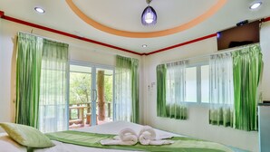 A hotel room with a bed, green curtains, a ceiling light, and a view of the outdoors. - Ingthara Resort (Phang Nga)