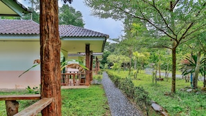 A rustic building with a tiled roof and a stone pathway leading to a wooden bench. - Ingthara Resort (Phang Nga)