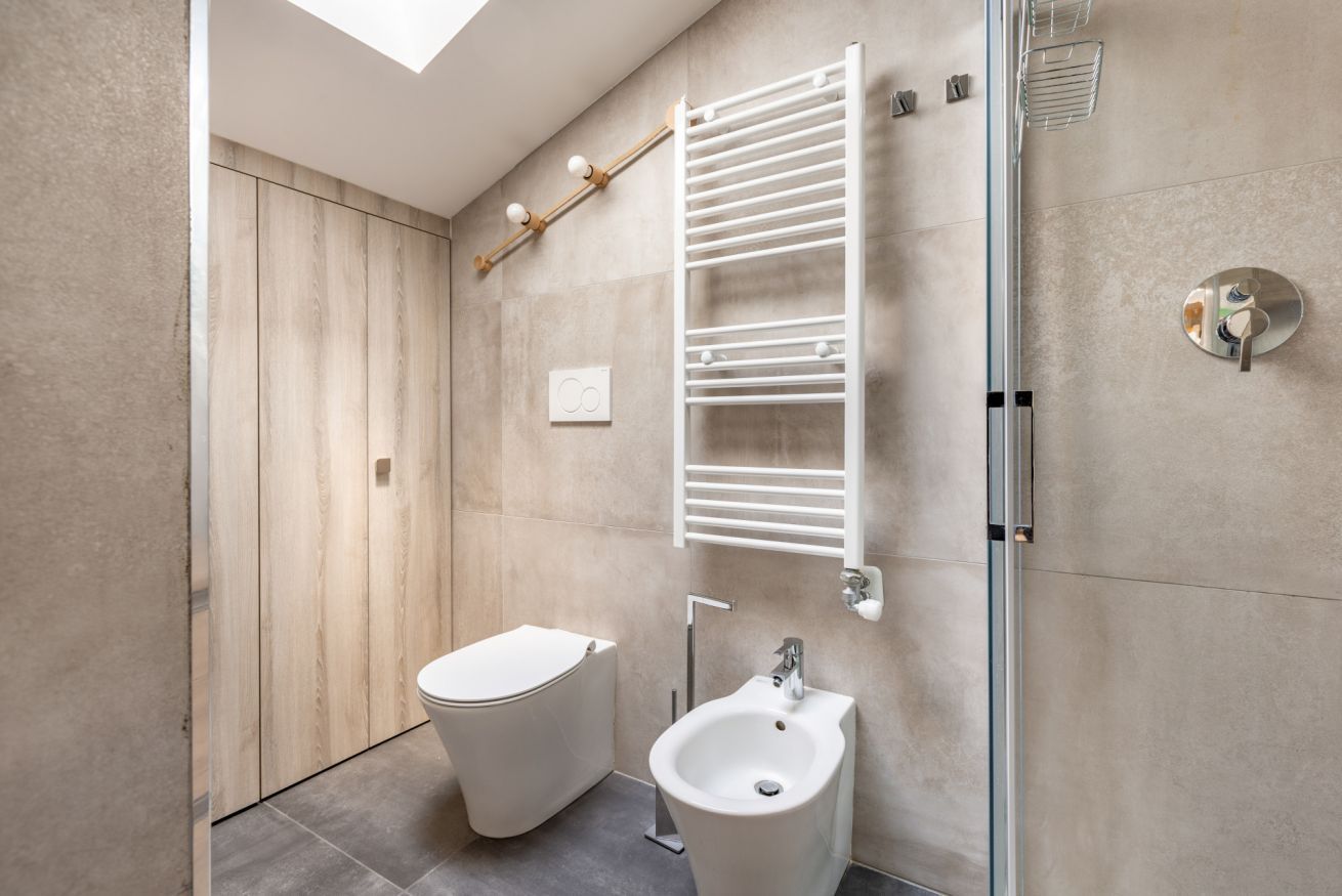 A modern bathroom with a toilet, bidet, and glass shower enclosure.