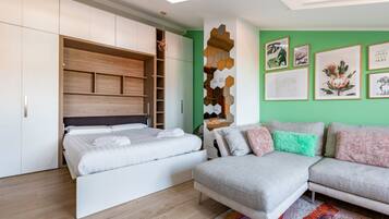A modern bedroom with a bed, a sofa, a built-in wardrobe, and a wall with framed artwork.