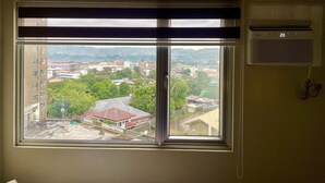 A window with a view of a cityscape, including buildings and greenery. - Avida Aspira Condotel (Cagayan de Oro)