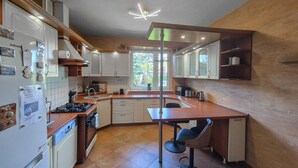 A modern kitchen with white cabinets, a gas stove, and a dining area with a table and chairs. - Pet friendly home in Warnoleka with WiFi (Warnoleka)